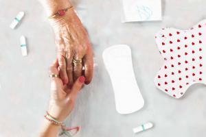 Mutter und Tocher halten Hände mit Menstruationsprodukte