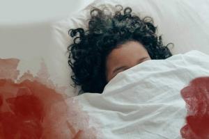 Frau im Bett mit Periodenblut