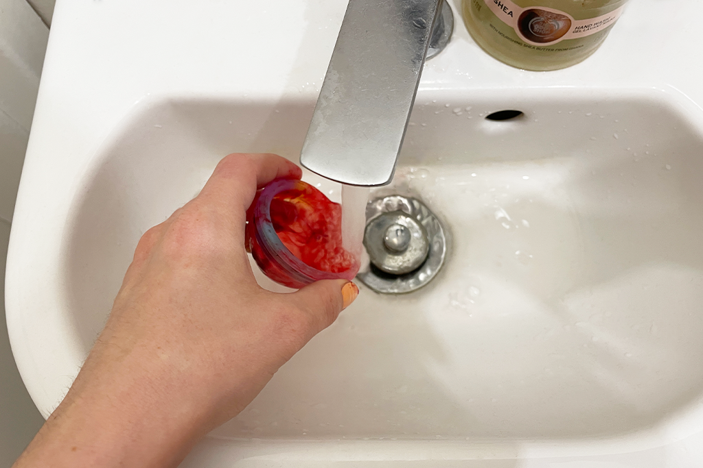 Menstruationsscheibe wird im Waschbecken mit Wasser ausgewaschen