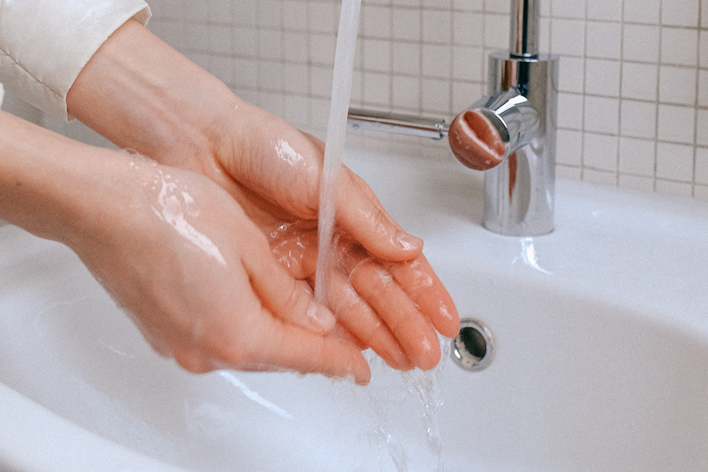 Person wäscht Hände beim Waschbecken