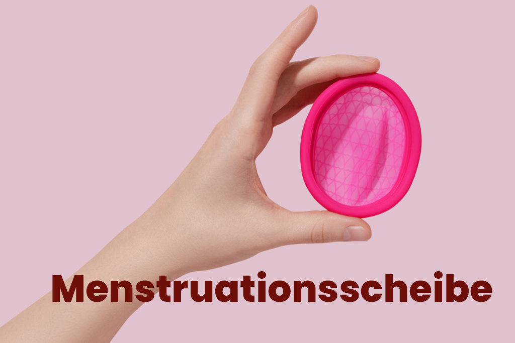 Hand zeigt eine ovalförmige, flache Tasse aus medizinischem Silikon (Menstruationsscheibe)