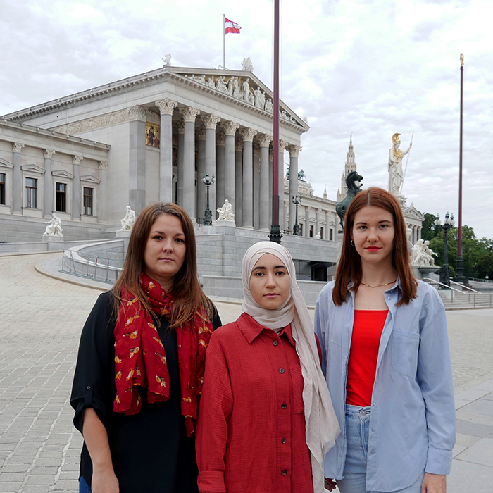 Drei Frauen von Plan International, der Bundesjugendvertretung und von der erdbeerwoche vor dem Österreichischen Parlament